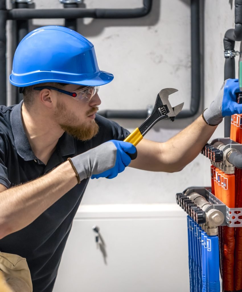 The technician checking the heating system in the boiler room. Adjusting heating valves in a residential building. A plumbing and heating technician works.